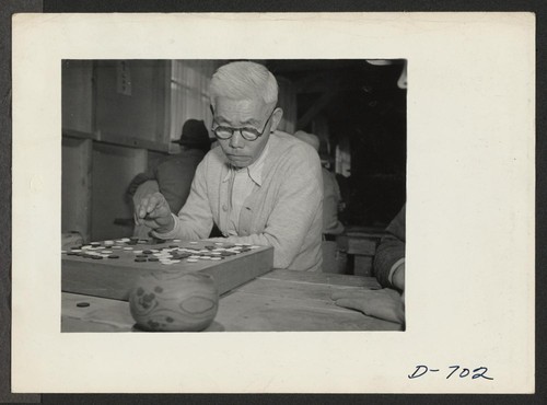 An evacuee of Japanese ancestry contemplates a move in the age-old Japanese game of Go. Photographer: Stewart, Francis Rivers, Arizona