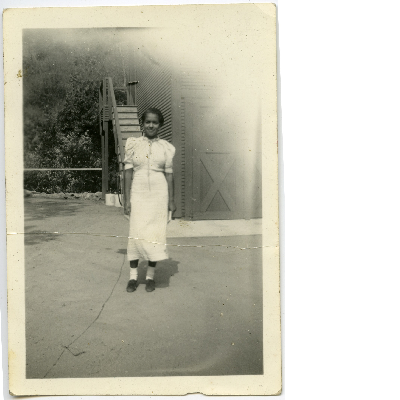 Unidentified woman standing next to house