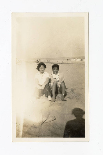 Young man and woman sitting together at the beach