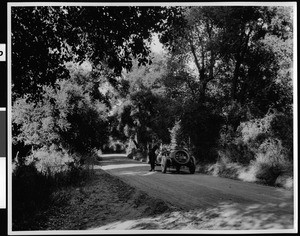 Man standing with his roadster along a narrow road between Descanso and Cuyamaca Park, ca.1928