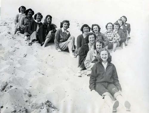 Teenage girls sitting in the sand in a letter y formation