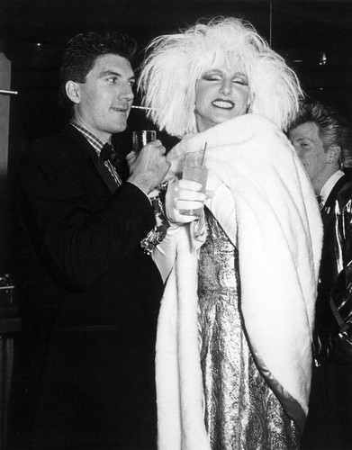 Todd Young dressed as a female impersonator, smiling and holding a drink