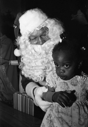 Tom Bradley in a Santa suit talking to a child, Los Angeles, 1982