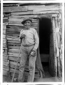 Yokut Indian man standing beside a shake house, Tule River Reservation near Porterville, California, ca.1900