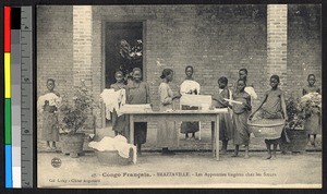 Young girls folding clothes outside of a brick building, Congo, ca.1920-1940