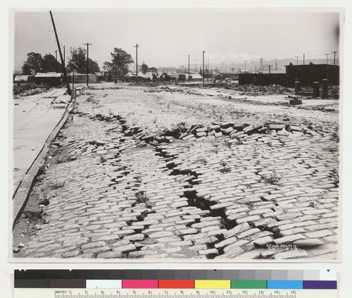 [Subsidence and fissures along street. Tents in distance (Columbia Square refugee camp?).]
