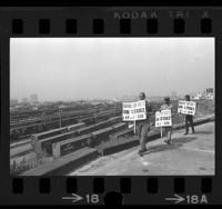 Three striking machinists picketing on hill overlooking freight trains at Taylor Yards in Los Angeles, Calif., 1967