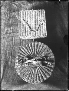 Two Indian baskets displayed on a cloth hanging, ca.1900