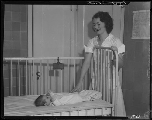 Nurse with baby in crib, Los Angeles, circa 1935