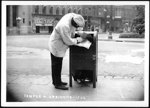 Man bending over a mail box on the corner of Temple Street and Spring Street in Los Angeles, July 1936