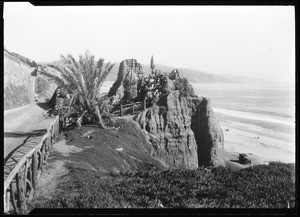 Automobile parked in front of a large rock outcropping on a cliff in Santa Monica's Palisades Park, 1910-1920