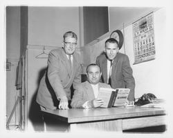 Three men looking at a copy of the Petaluma City directory, Petaluma, California, 1955