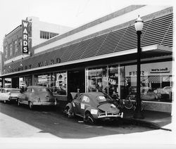 Wrecked Volkswagen advertising Bud Leete Body Shop in front of Montgomery Ward, Santa Rosa, California, 1961