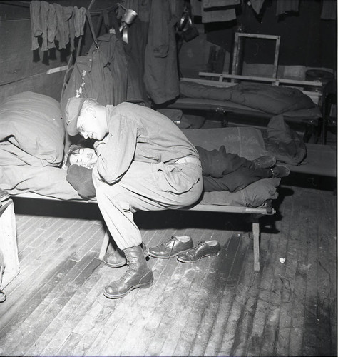 Soldiers leaning over woman in barracks