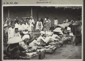 Market in Borneo. Malay women selling food. On the right a dajak woman from the hinterland with a carrying-basket on her back (1926)