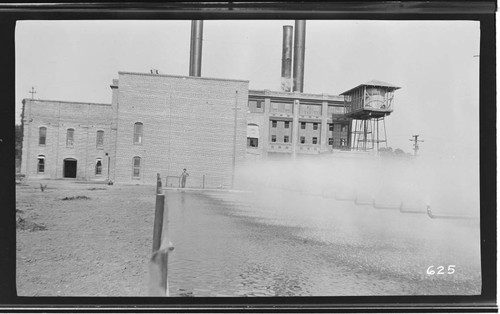 An operator standing outside of the Visalia Steam Plant by the cooling pond