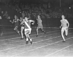 Analy High School Tigers track, 1960s--runner Phil Ito breaking the tape at a night time track meet