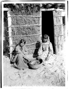 Two young Chemehuevi Indian girls making a drink from mesquite beans, ca.1900
