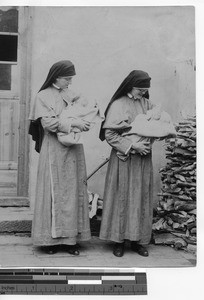 Two Maryknoll Sisters holding baptized infants at Yangjiang, China, 1923
