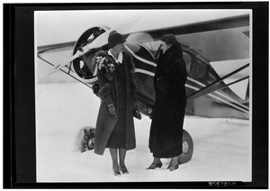 Amelia Earhart and Loretta Schimmoler standing in front of an airplane, 1937