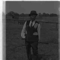 An man in a field astride a broom