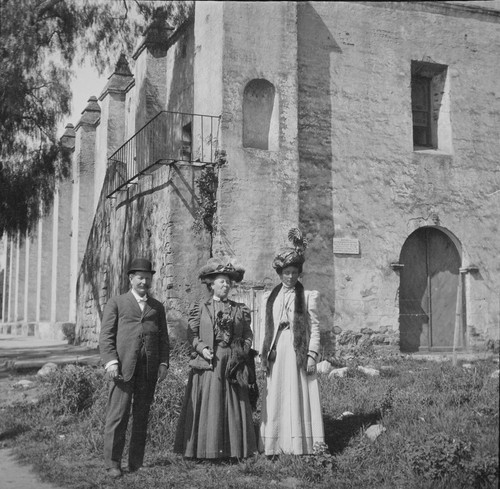 Man and two women standing near a mission