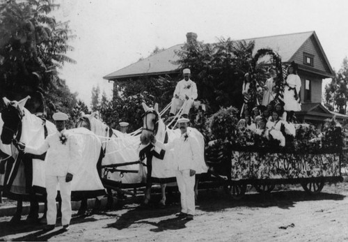 Float in parade in front of George and Hattie Peters' house on 110 W. 1st St