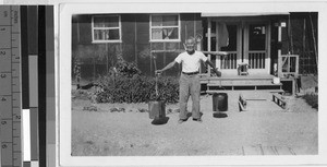 Man carrying buckets on a pole, Jerome Relocation Center, Denson, Arkansas, ca. 1943
