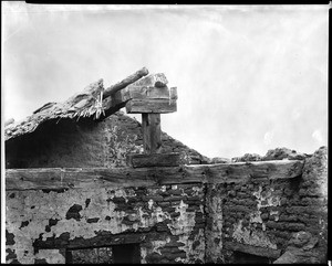 Roof beams of one of Mission San Fernando's shops, looking south from the church bell towers, ca.1898