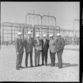Men in suits (with and without hardhats) receiving a plaque or award at a transmission substation