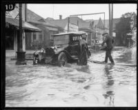 Man crossing flooded Pico Blvd. to get to car, Los Angeles, 1926