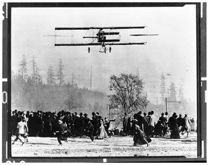 Biplane flying low over a crowd of onlookers