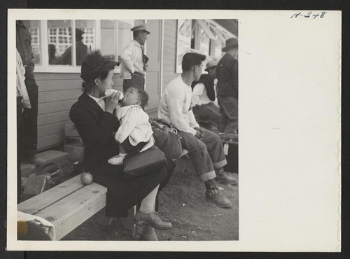 A mother from the Jerome Center feeds her baby while waiting for the truck to take her to her new quarters. Photographer: Mace, Charles E. Newell, California