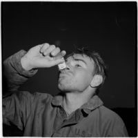 Sailor takes a swig of brandy from a tiny bottle during the Army-Navy maneuvers that took place off the coast of Southern California in late 1946