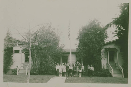 Children stand with the American flag in front of Canyon School (in Santa Monica Canyon) during World War II