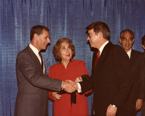 Margaret Brock watches George Deukmejian and Bill Hawkins shake hands