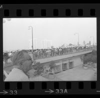 Onlookers and protesters await President Johnson's motorcade on Avenue of the Stars in Century City, 1967
