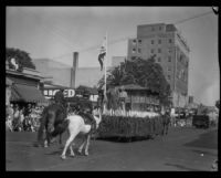 Float with costumed riders and flags in the parade of the Old Spanish Days Fiesta, Santa Barbara, 1930