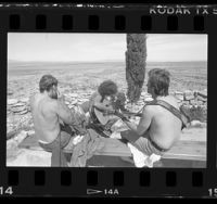 Three inmates playing guitars and harmonica on hilltop overlooking the desert at Boron Federal Prison, Calif., 1986
