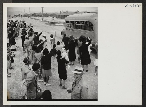 A crowd of Topaz Center residents wave farewell as one of the buses, City of Topaz, leaves the assembly center on it's way to Delta, Utah, with passengers for trip 15 leaving for Tule Lake. Photographer: Mace, Charles E. Topaz, Utah