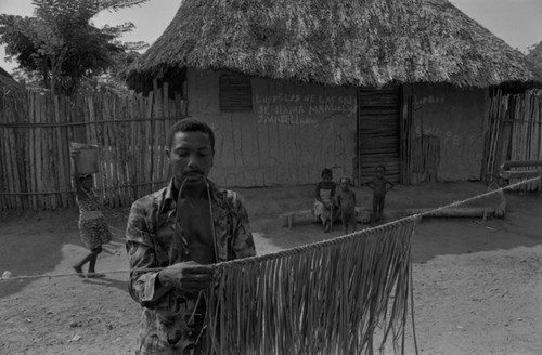 Man braiding palm leaves for a broom, San Basilio de Palenque, 1977