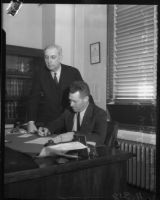 Officer Frank E. Walker provides his signature on a document with Deputy District Attorney Howard R. Hinshaw present, Los Angeles, 1930s