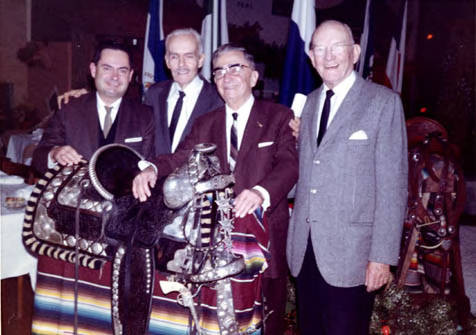 Presentation Party held in the Latin American Mart in Olvera Street with Eugene Biscailuz, Sheriff Zmeritus, Warren, son of Eugene Biscailuz, and Ricardo F. Hopping, art director of El Pueblo de Los Angeles. Sheriff Zmeritus is shown with his hands on the saddle he rode in traditional parades, it is going to be displayed with Italian antiques