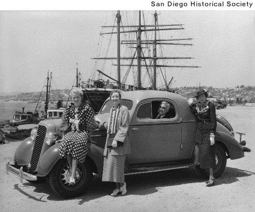 Three women with a 1932 Chevrolet parked near the Star of India