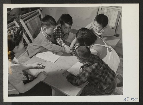In a pre-school class at the Jerome Center, young residents reach for the crayon box, under the supervision of assistant teacher Emiko Shinagawa. Children, left to right, are: Hidemi Kimura, Tomiko Fukute, Shigea Konishi, Alfred Miyamoto, and Sei Asaki. Photographer: Parker, Tom Denson, Arkansas
