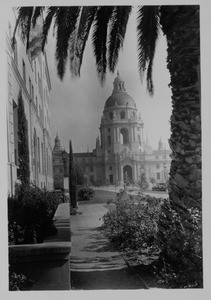 A front of the Pasadena City Hall cropped by a palm tree, ca. 1930