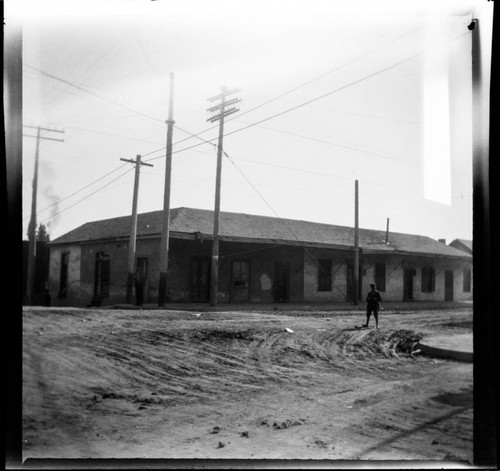 Adobe building on street corner with boy standing at right