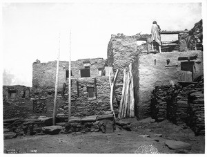 Hopi Indian woman on top of her adobe house as she enlarges it in the village of Oraibi, ca.1901