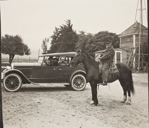 Laura Mae Stewart and passenger in the car, with her father Rez Stewart on horseback