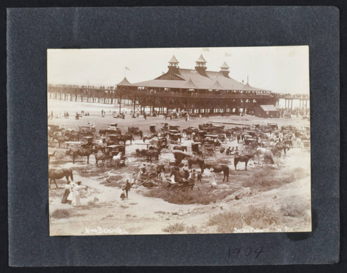 People with horses and carriages on the beach in front of the Pavilion